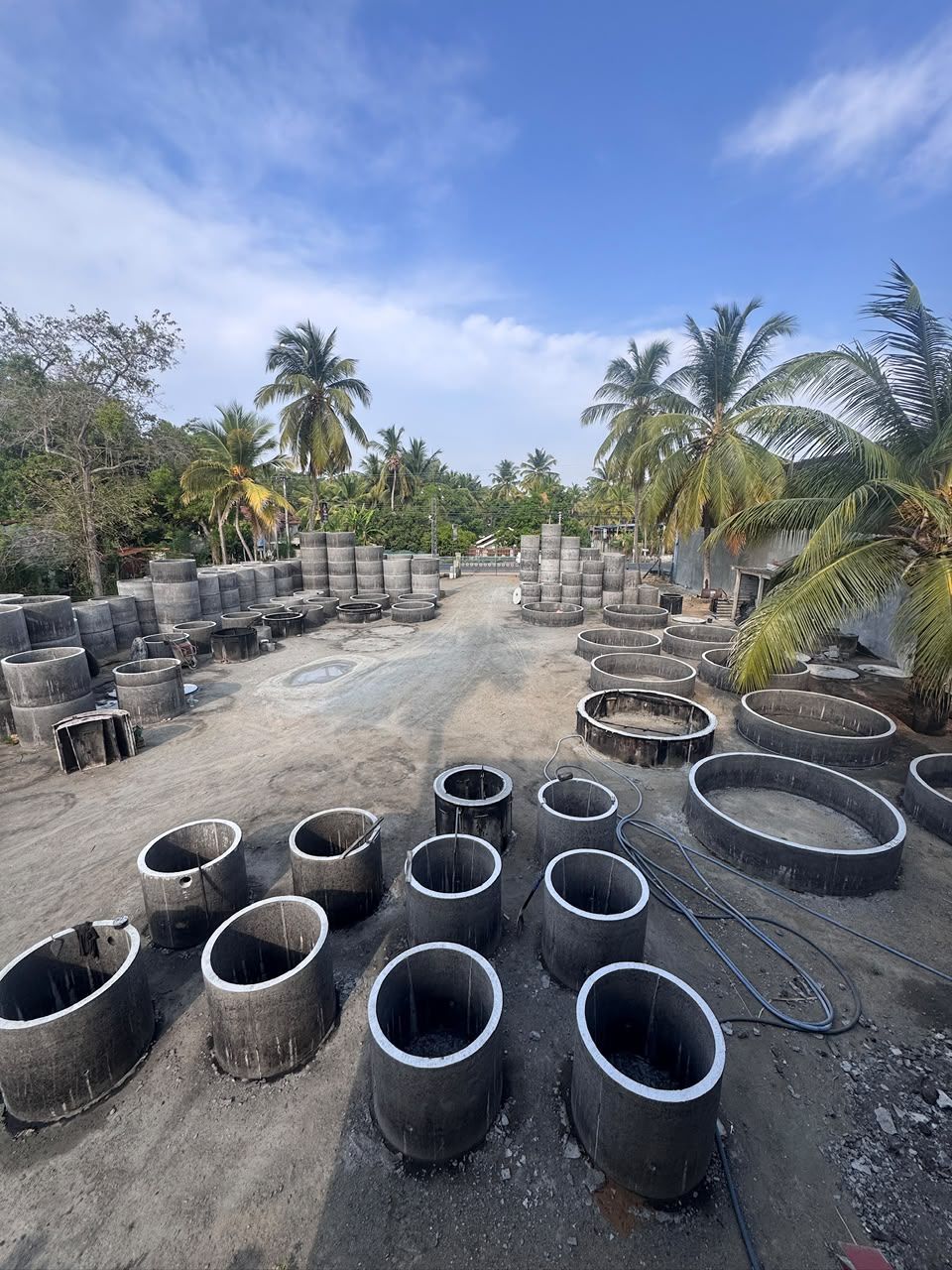 The Ajith Concrete yard in Embilipitiya from above: filled moulds on the casting floor in front, finished rings stacked at the back