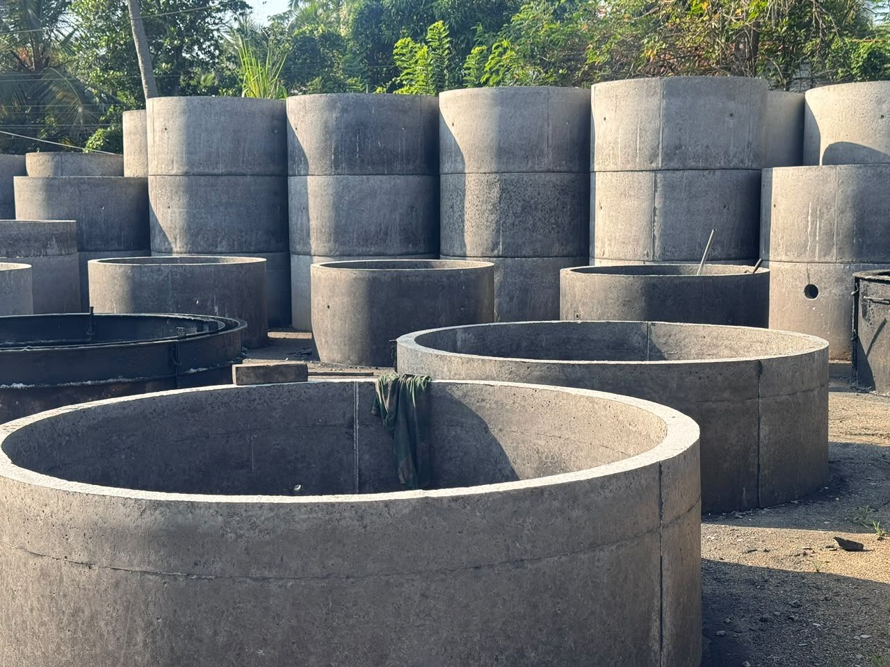 Concrete well rings of several widths in the Ajith Concrete Works yard in Embilipitiya, some stacked two high