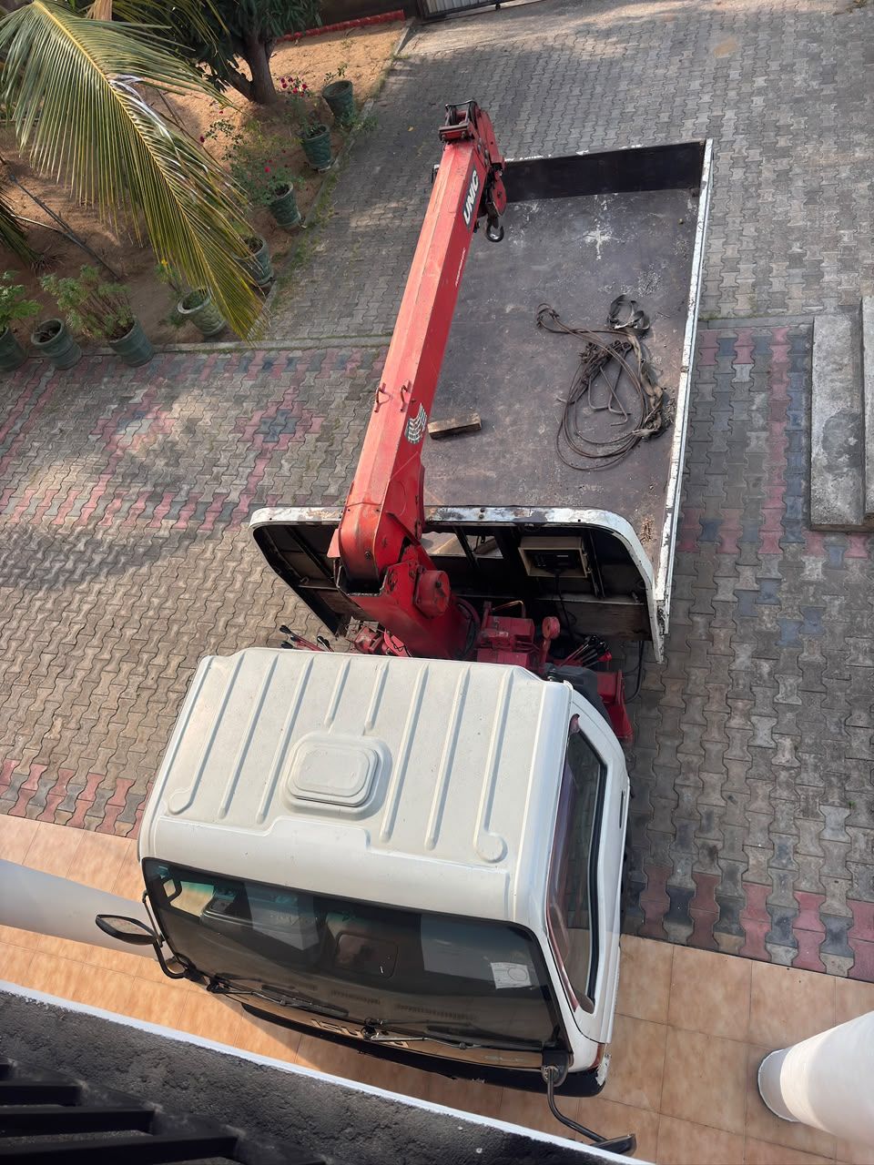 The Ajith Concrete delivery lorry seen from above, with its red hydraulic crane folded behind the cab