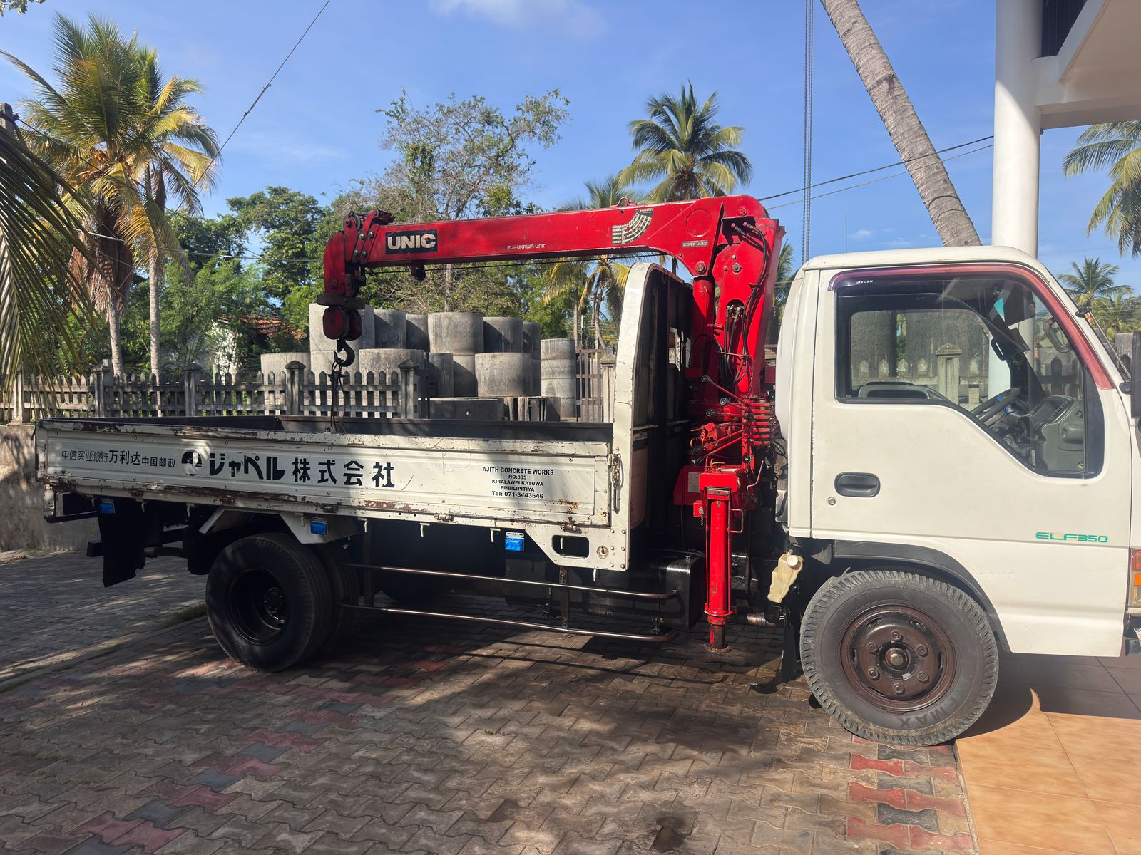 The Ajith Concrete Works lorry with its red UNIC hydraulic crane, the yard's name, address and phone number painted on the side