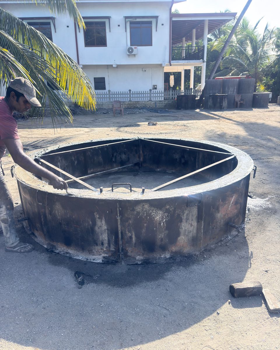 ශක්තිමත් කළ වානේ අච්චුවක ඇති විශාල කොන්ක්‍රීට් වළල්ලක් පරීක්ෂා කරන සේවකයෙක්, පිටුපසින් ක්‍රේන් ලොරිය