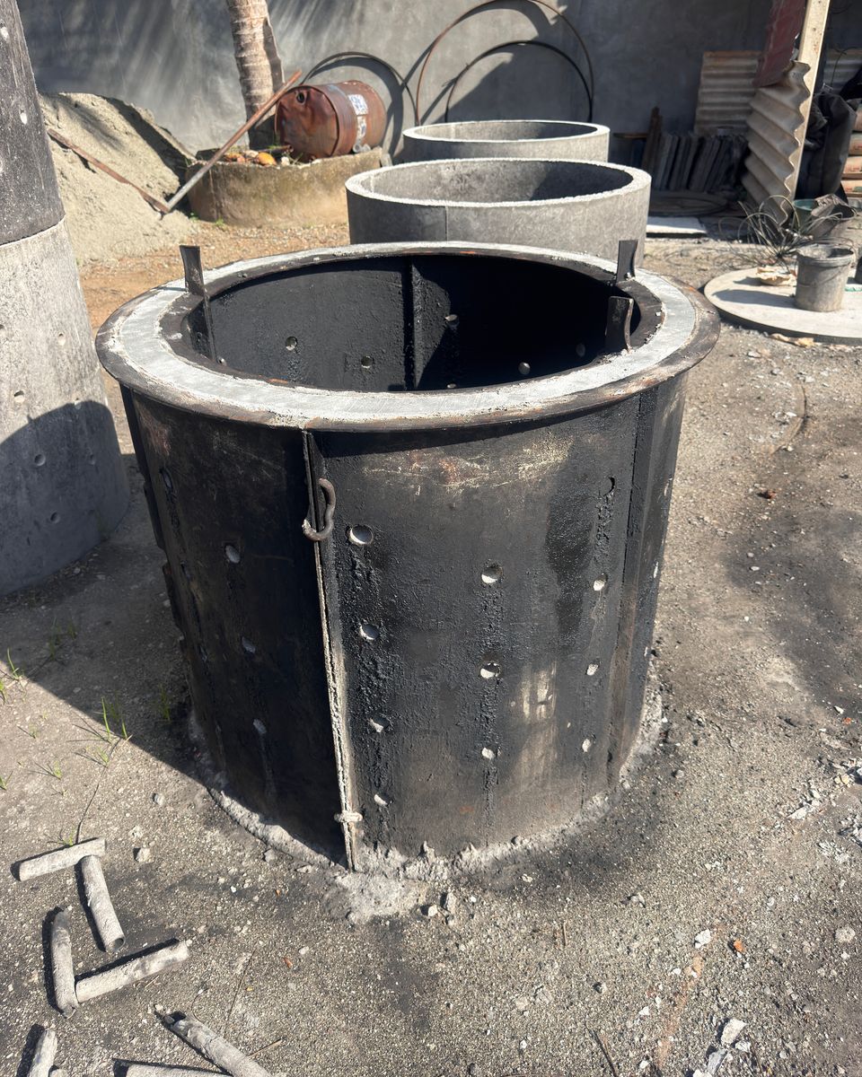 A steel mould for a soakage ring in the Ajith Concrete Works yard, with the pins that form its holes on the ground in front