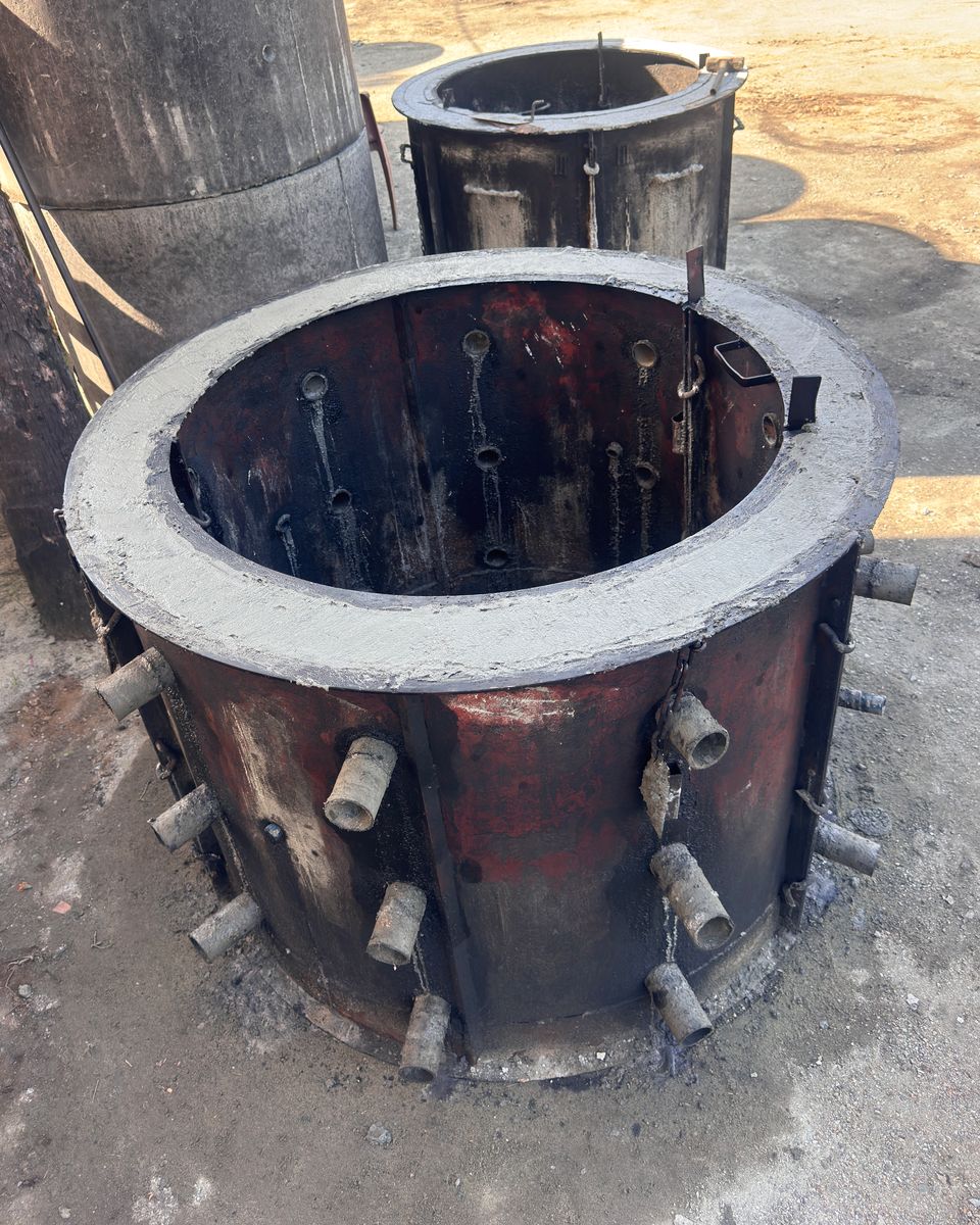 A steel mould for a soakage ring, just filled, with the pins that form the holes set through both shells