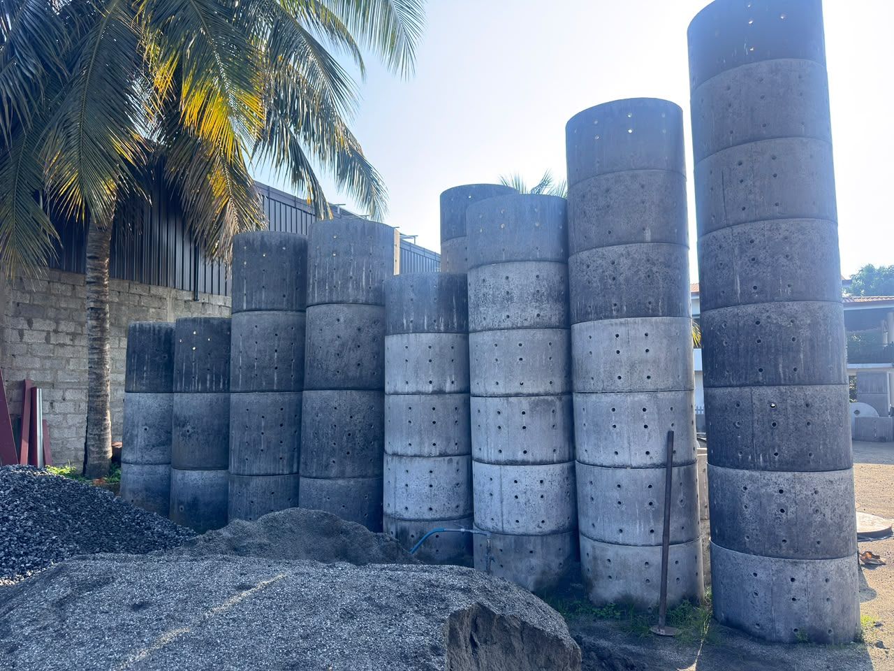 Concrete soakage rings stacked in tall columns in the yard, the tallest many rings high