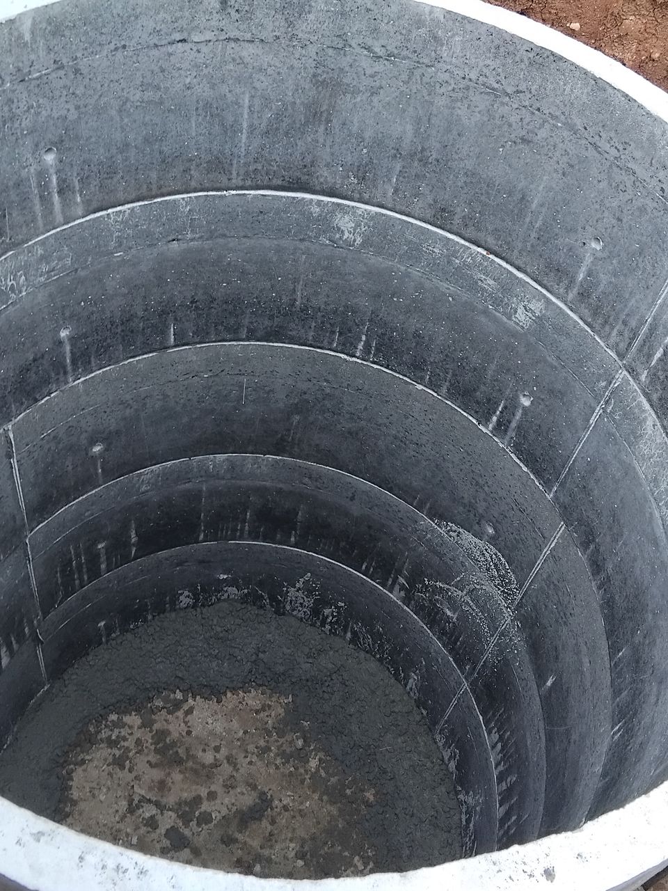 Looking down into a stack of concrete rings in the ground, its joints lined up