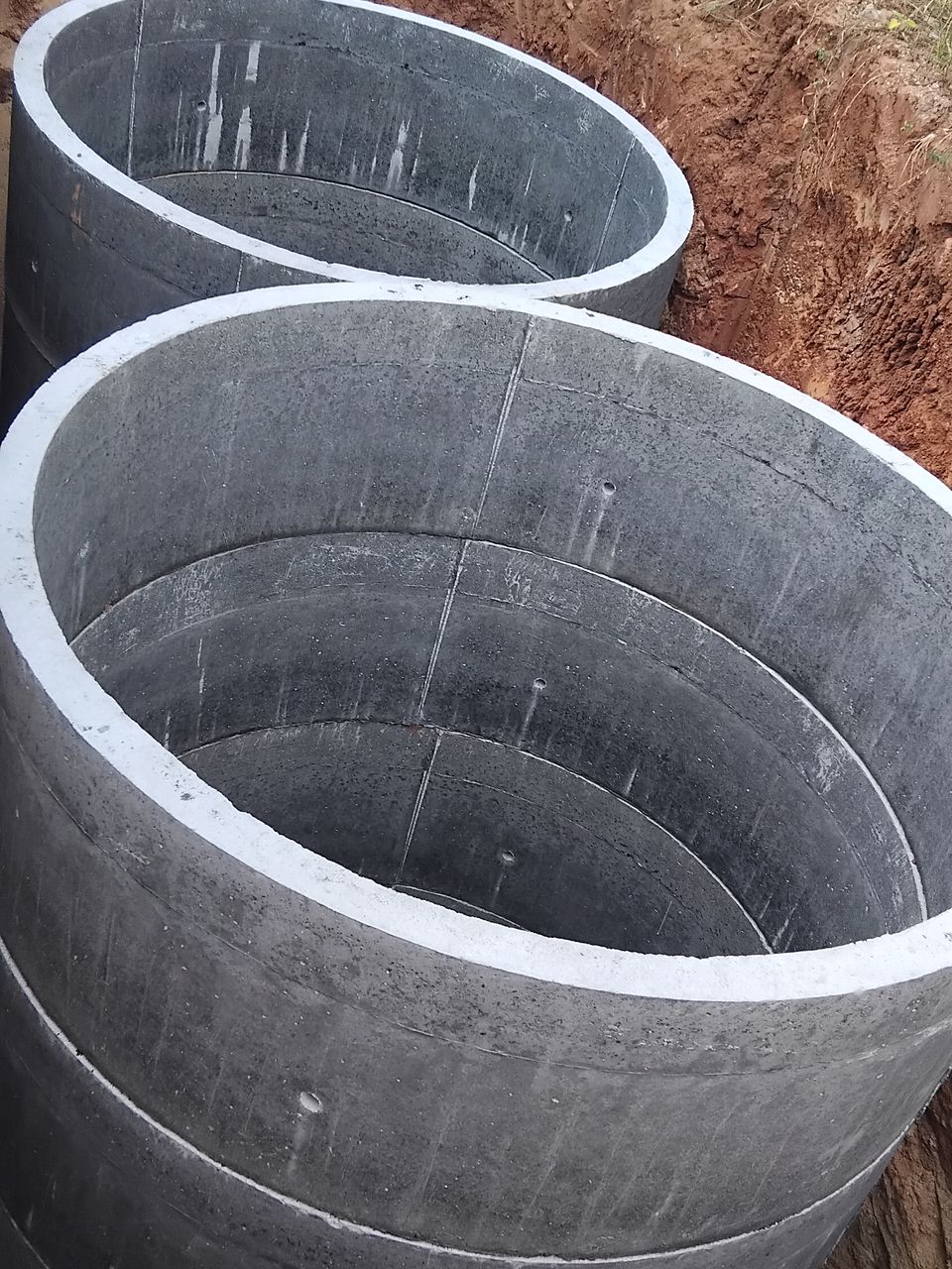 Two stacks of concrete rings in a pit, the nearer one reaching the top