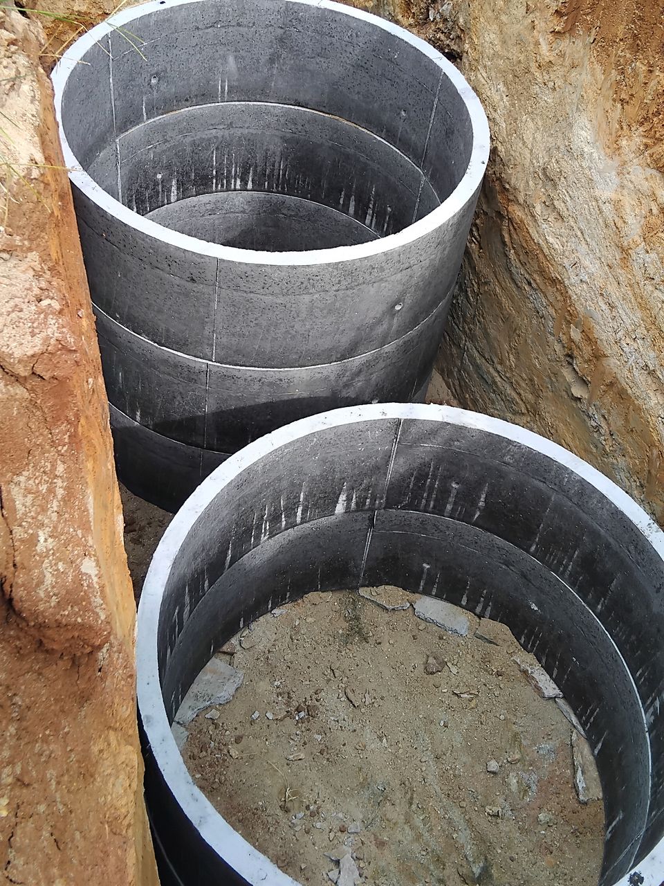Two stacks of concrete rings set side by side in a dug pit